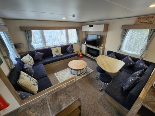 een woonkamer met een blauwe bank en een tafel bij 2 Bed Caravan With Decking in Saint Osyth