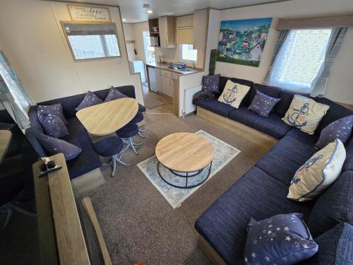 een woonkamer met een blauwe bank en een tafel bij 2 Bed Caravan With Decking in Saint Osyth