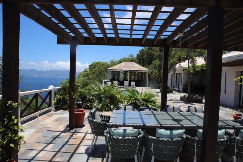 a patio with a table and chairs and a view of the water at Rock House Estate in Bequia