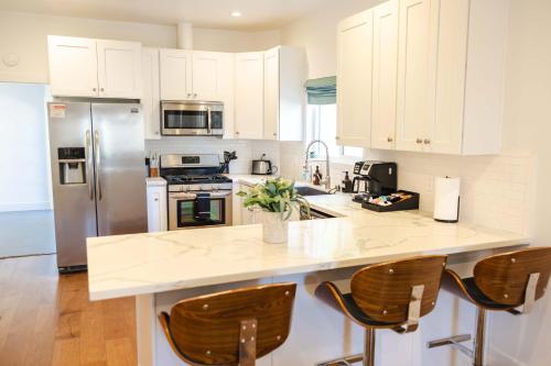 a kitchen with white cabinets and a counter with chairs at Mid Century Modern - Walk to Dodger Stadium, DTLA in Los Angeles
