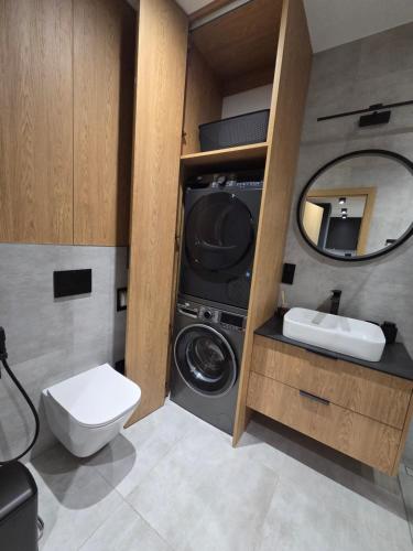 a bathroom with a washing machine and a sink at Parkowa Prestige Apartament in Grajewo