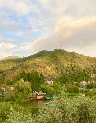 a boat on a river in front of a hill at Lake side stays in Srinagar