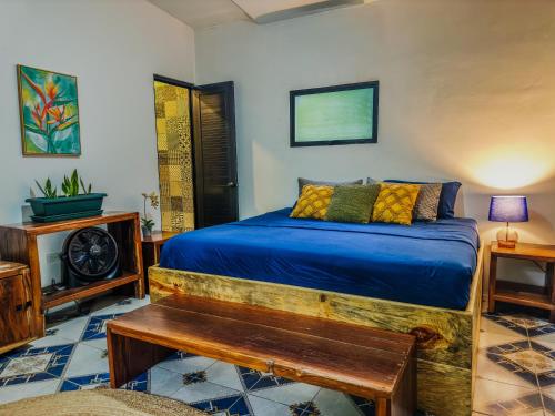 a bedroom with a bed with blue sheets and a table at Greengos Hotel in Lanquín
