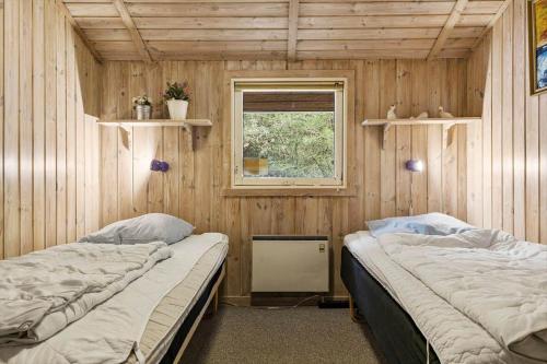two beds in a room with wooden walls and a window at 0011-Romo-Trinnesvej-9 in Bolilmark