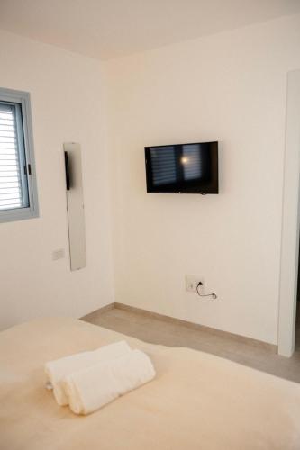 a bedroom with a bed with a tv on the wall at תמול שלשום - צימר בירוחם ברחוב עגנון in Yeroẖam