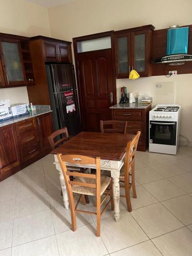 a kitchen with a wooden table with chairs and a stove at Mbibo Farmhouse in Mityana