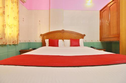 a bedroom with a large white bed with red pillows at Hotel O IBRAS Residency Trichy in Fort