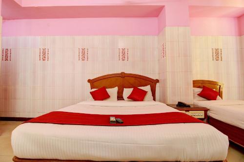 a bedroom with a large bed with red pillows at Hotel O IBRAS Residency Trichy in Fort