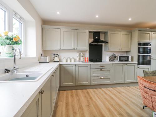 a kitchen with white cabinets and a wooden floor at Fields View in Tamworth