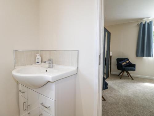 a bathroom with a white sink and a chair at Fields View in Tamworth