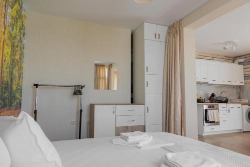 a white room with a bed and a kitchen at Просторен апартамент за семейна почивка in Hisarya