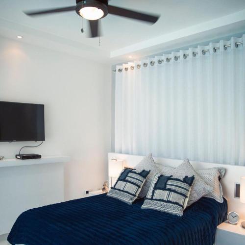 a bedroom with a bed with pillows and a ceiling fan at RED HEART 3 BEDROOMS OCEAN VILLAGe in Puerto Plata