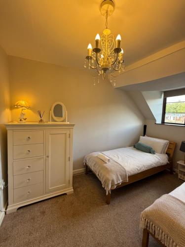 a bedroom with a bed and a chandelier at Bewdley River Cottage - Free private gated parking for 2 cars - River front location in Bewdley