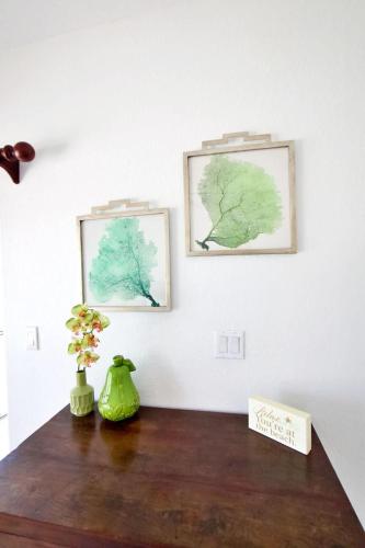 a table with two pictures on the wall and a vase with flowers at 7 Up Condo at Kaibo Kai in Driftwood Village