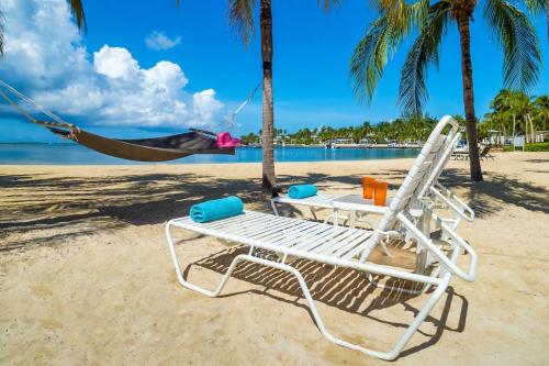 a hammock and a chair on a beach at 7 Up Condo at Kaibo Kai in Driftwood Village