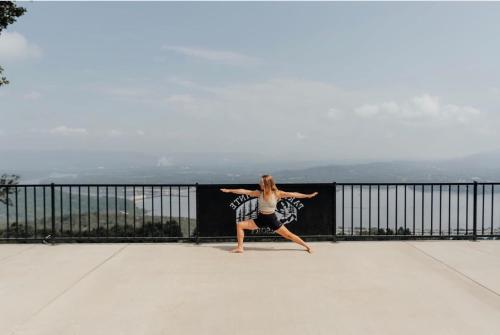 a woman standing on a balcony with her arms out at Cloud 9 Cabin with an indoor pool hot tub & fire pit in Bryant