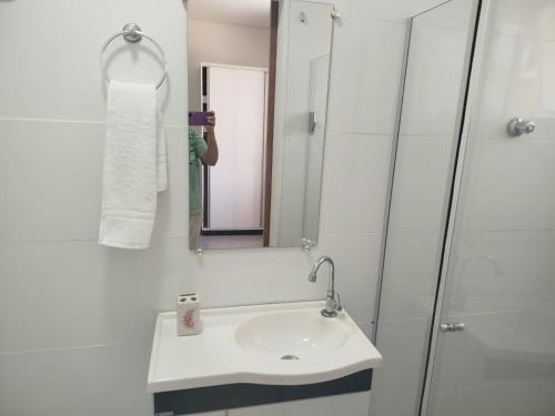 um banheiro branco com uma pia e um espelho em casa Moderna com Ar do Campo em Contagem