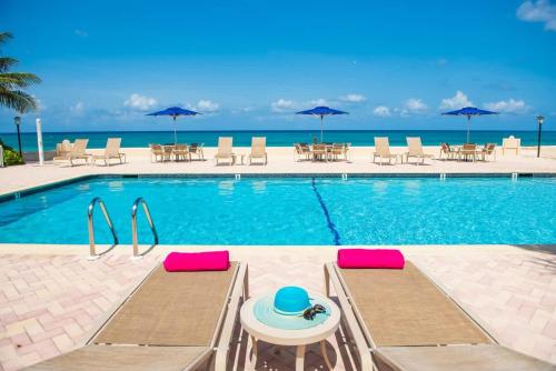 a swimming pool with chairs and tables and umbrellas at Georgetown Villas #113 in Seven Mile Beach