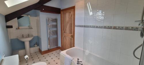a bathroom with a tub and a toilet and a sink at Brynderwen Barn in Llangorse