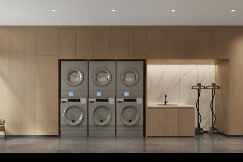 a laundry room with four washing machines and a counter at Fairfield by Marriott Dalian Jinpu New Area in Dalian