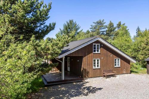 a wooden cabin with a porch in the woods at 2608-Romo-Sonderstrandvej-18 in Mølby