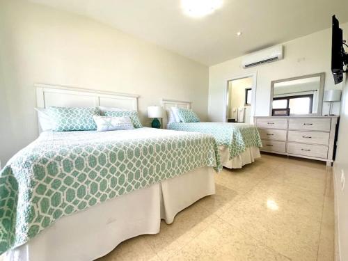 a bedroom with two beds with green and white comforters at Seven Mile View Condo #4 in West Bay
