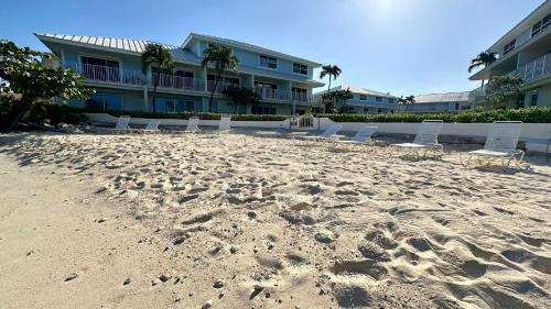 a sandy beach with lounge chairs and a building at Grape Tree Condo #10 in George Town