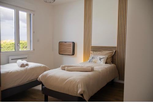 two beds in a room with a window at Truffiers Charentais Résidence in Val-de-Bonnieure