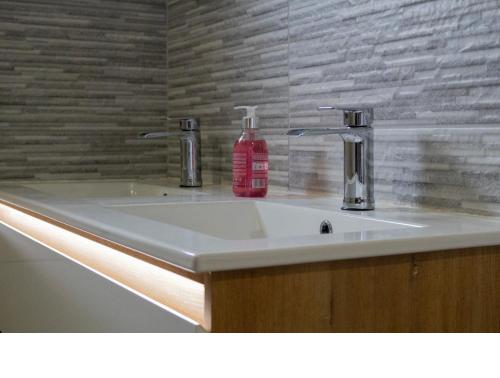 a bathroom sink with a red soap bottle on it at Truffiers Charentais Résidence in Val-de-Bonnieure