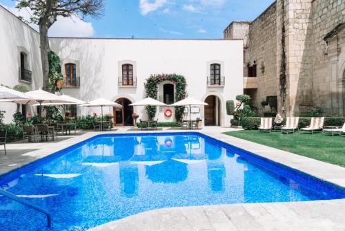 a swimming pool in front of a building with a house at Quinta Real Oaxaca in Oaxaca City