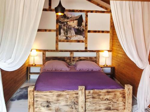 a bedroom with a wooden bed with purple sheets at Etno wooden room in Rakovica