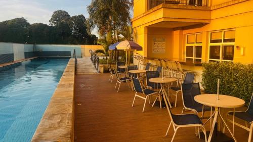 a patio with tables and chairs next to a swimming pool at Studio Guarulhos 208 in Guarulhos