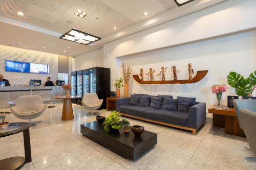 Una sala de estar con un sofá azul y sillas. en BEIRA MAR- FLAT EXECUTIVE, en Recife