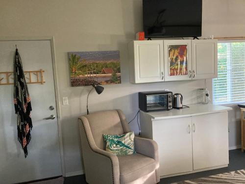 a room with a chair and a tv and a door at Comfort Nest in Pahoa