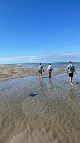 three people walking in the water on the beach at Strandhuisje Anna dicht bij de zee in Ouddorp