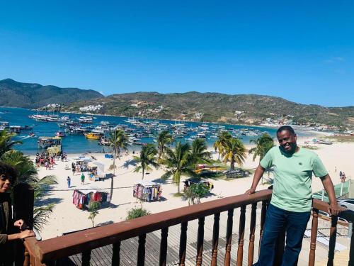 a man standing on a balcony overlooking a beach at pe na areia in Arraial do Cabo