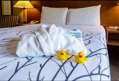 two rubber ducks sitting on a bed with towels at Pemberton Valley Lodge in Pemberton