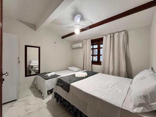 ein Schlafzimmer mit zwei Betten und einem Deckenventilator in der Unterkunft Condomínio Ouro – Piscina e Praia a Poucos Passos in Porto Seguro