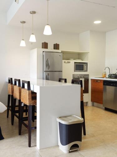 a kitchen with a white island in a kitchen with chairs at Beach Apartment Nikki Steps From The Sea in El Chirú