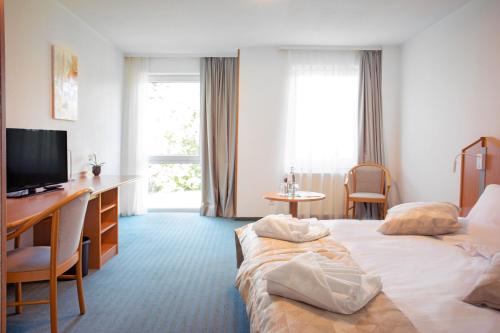 a hotel room with two beds and a desk and a television at Hotel Bessunger Forst in Roßdorf