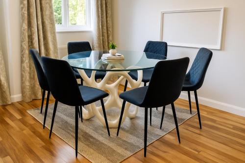a dining room with a glass table and chairs at Modern 3-Bedroom Home with Free Parking for Family, Contractors and Tourists! in Sittingbourne