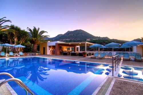 a swimming pool with blue umbrellas and a resort at Xidas Garden in Balíon