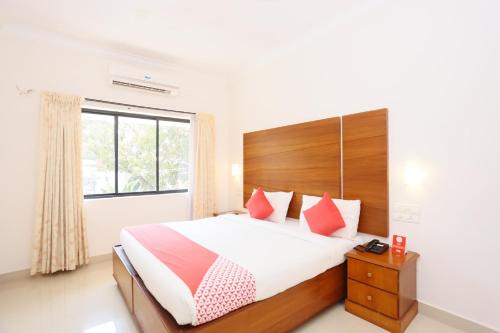 a bedroom with a large bed and a window at Super Townhouse Dona Castle in Kollam