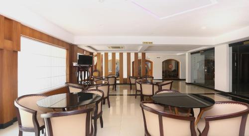 a restaurant with tables and chairs and a television at Super Townhouse Dona Castle in Kollam