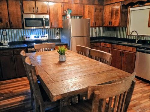 a kitchen with a wooden table with chairs and a refrigerator at Wild Mountain Lodge in Sevierville