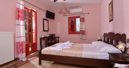 a bedroom with a bed with white sheets and red windows at Arolithos Traditional Village Hotel in Tílisos
