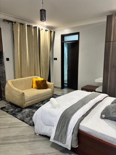 a bedroom with a large bed and a chair at CALM STAYs in Kampala