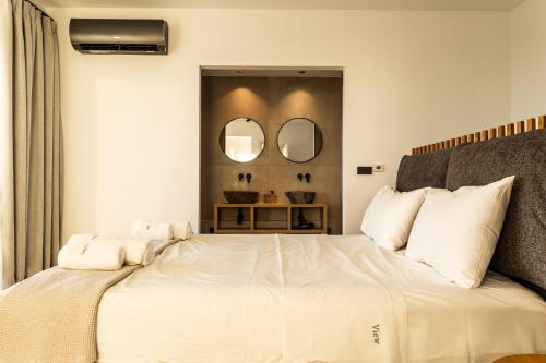 a bedroom with a large white bed with two mirrors at The View Premium Villas in Perdika