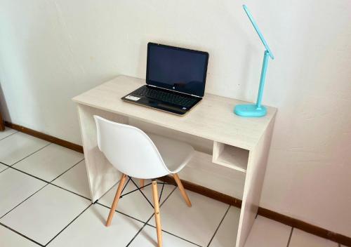 a laptop computer sitting on a desk with a chair at Hermosa casa frente a la playa in Same