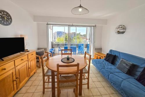 ein Wohnzimmer mit einem Tisch und einem blauen Sofa in der Unterkunft T2 Cosy à 800mètres de la mer in Saint-Jean-de-Monts